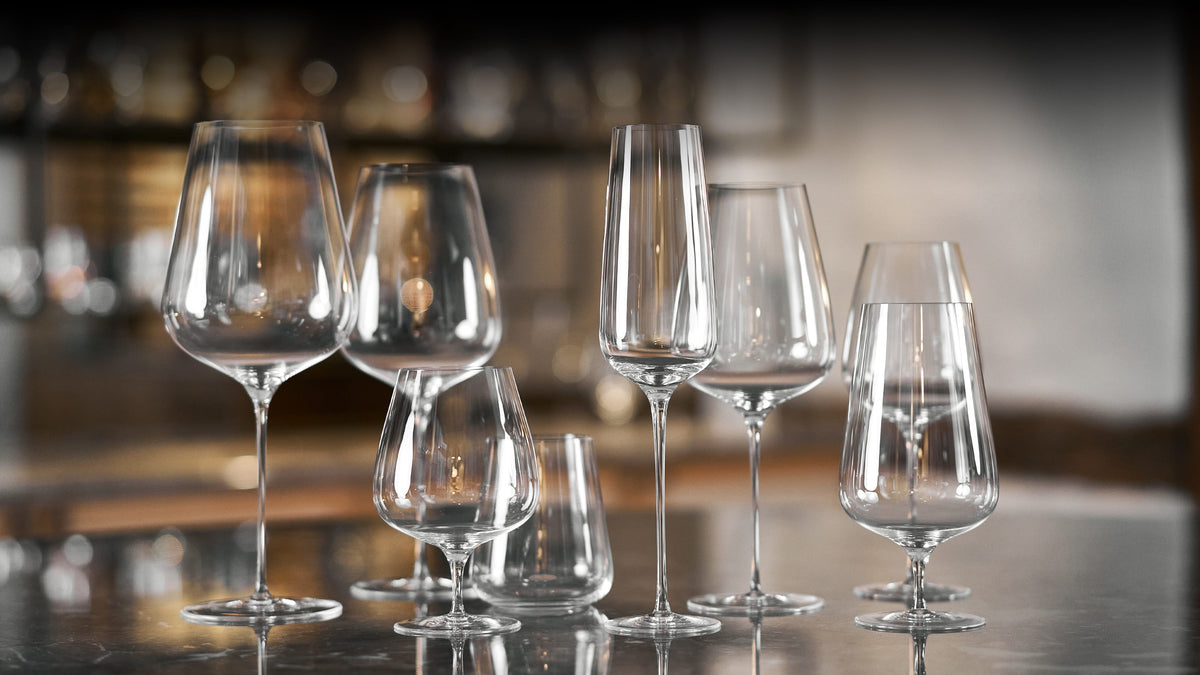 Seks forskellige tydeligt facetslebne krystalglas i klart glas til vin, champagne og vand på åbent bord