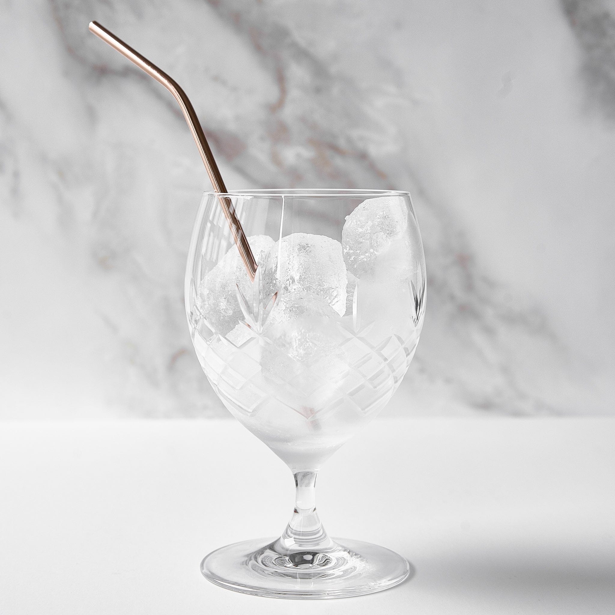 Facetslebet drikkeglas i klart krystalglas med diamantmønster fra Frederik Bagger med isterninger og metal sugerør