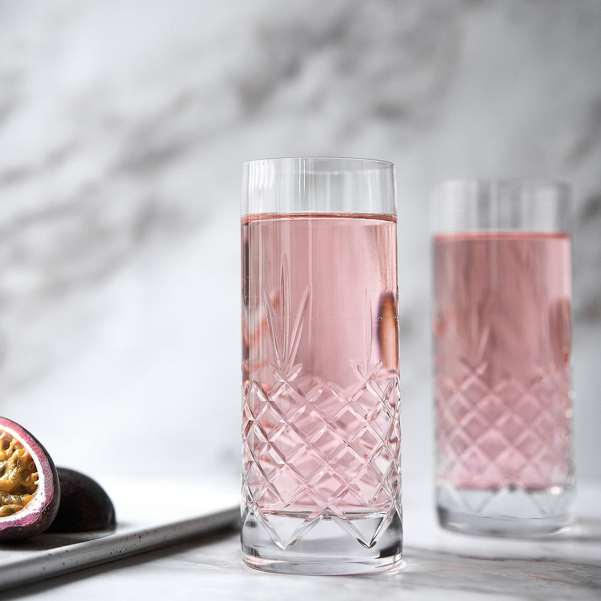 To facetslebne krystal highballglas med diamantmønster fyldt med lyserød drik til borddækning fra Frederik Bagger