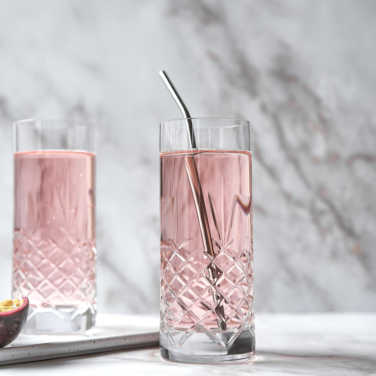 To klare facetslebne Crispy highballglas med diamantmønster fyldt med lyserød drik fra Frederik Bagger