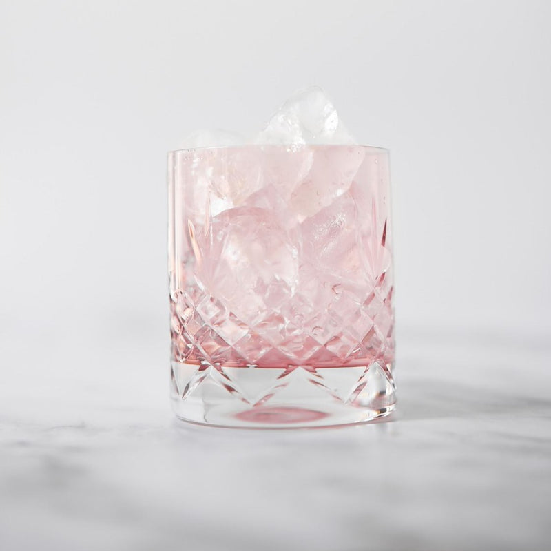 Facetslebet lowballglas i rosa krystalglas med riflet diamantmønster fyldt med is på marmorbord fra Frederik Bagger